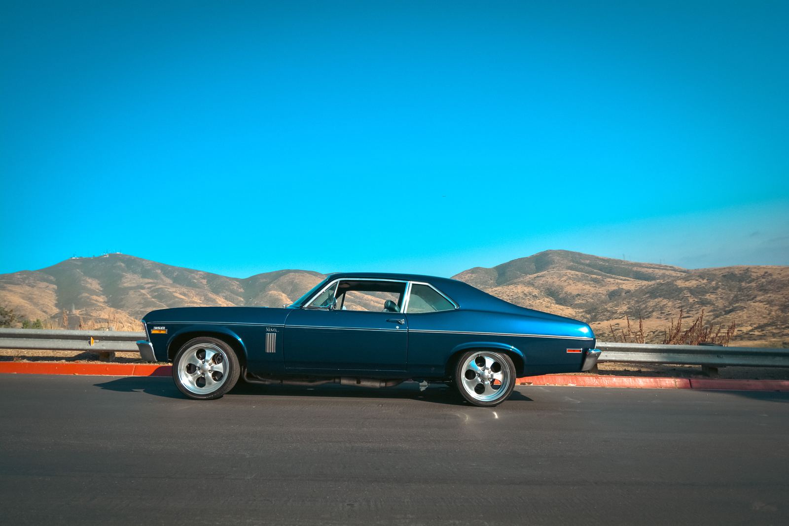 Classic muscle car on an open road with mountains behind