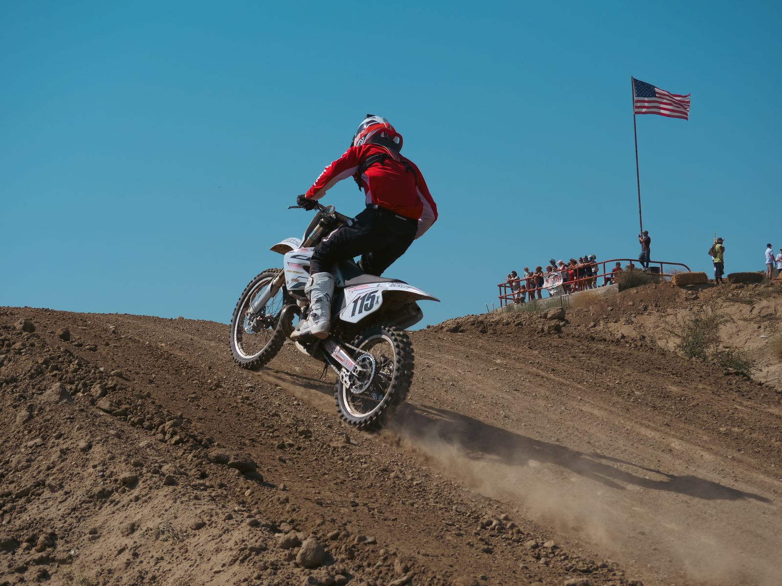 Rider cresting a hill with an American flag behind