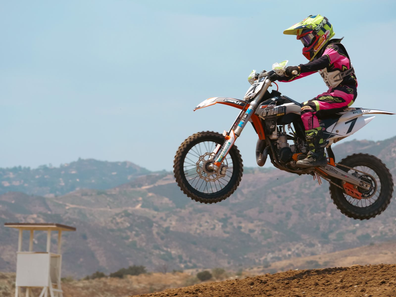 Motocross rider in pink gear mid-jump