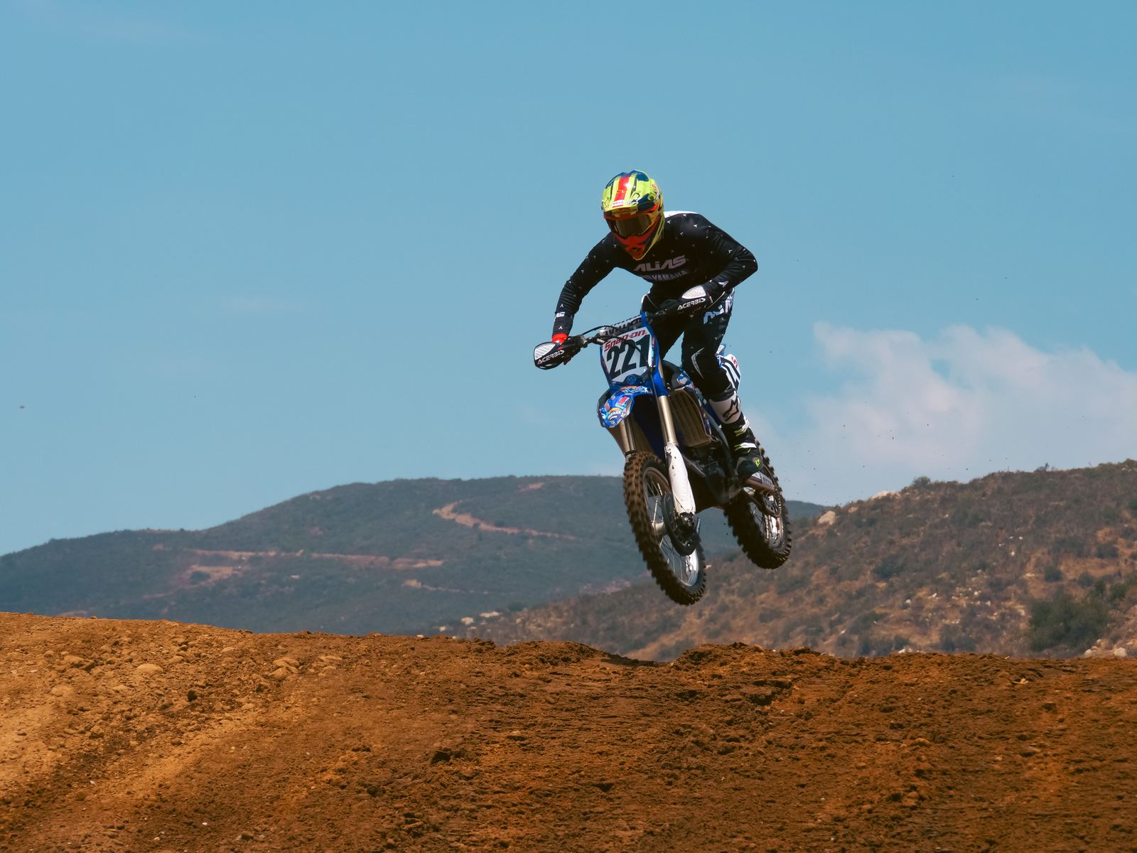 Motocross rider airborne against a blue sky