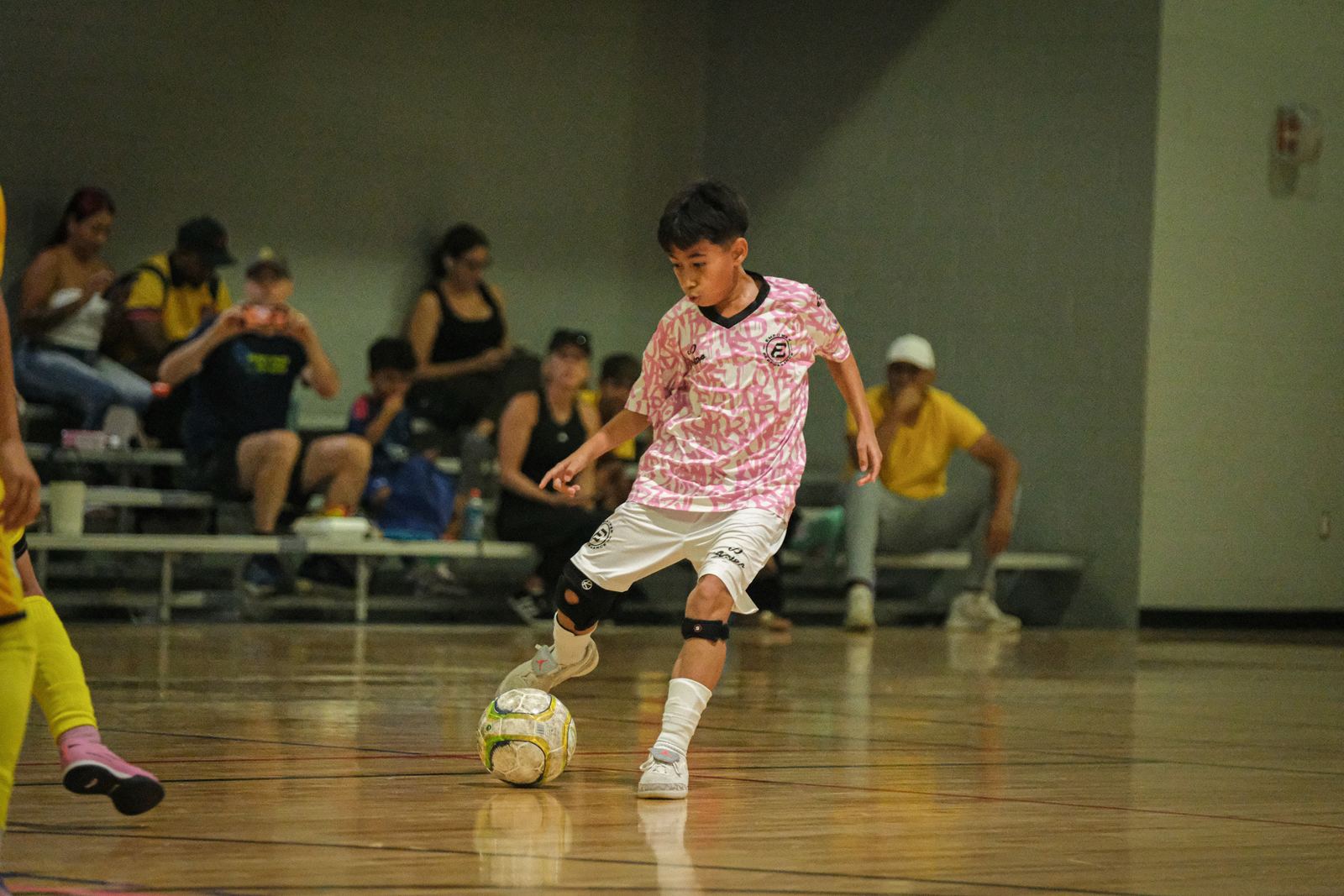 Player in a pink EmPower kit dribbling past a defender during a league game