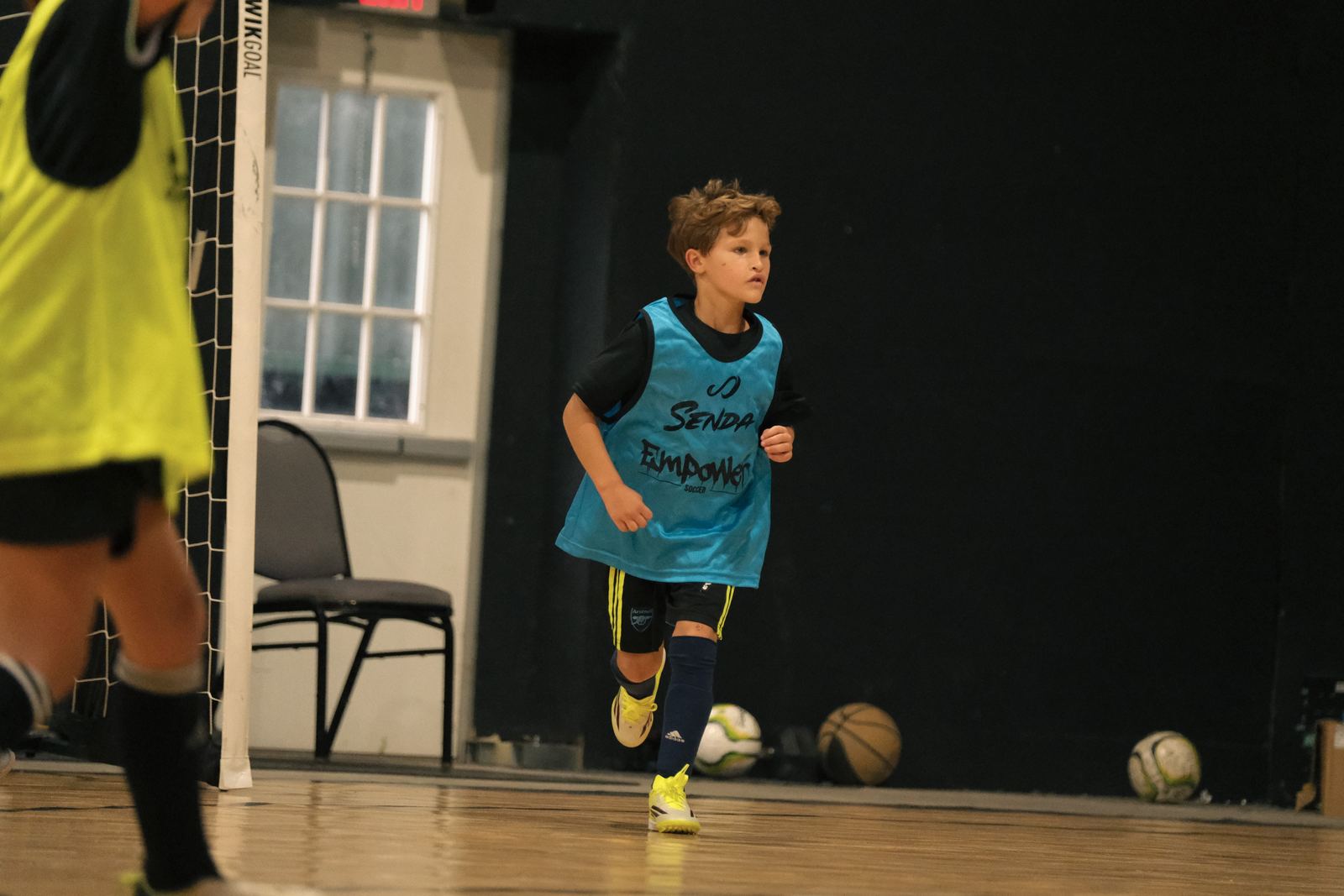 Youth player in a training bib striking the ball in the gym